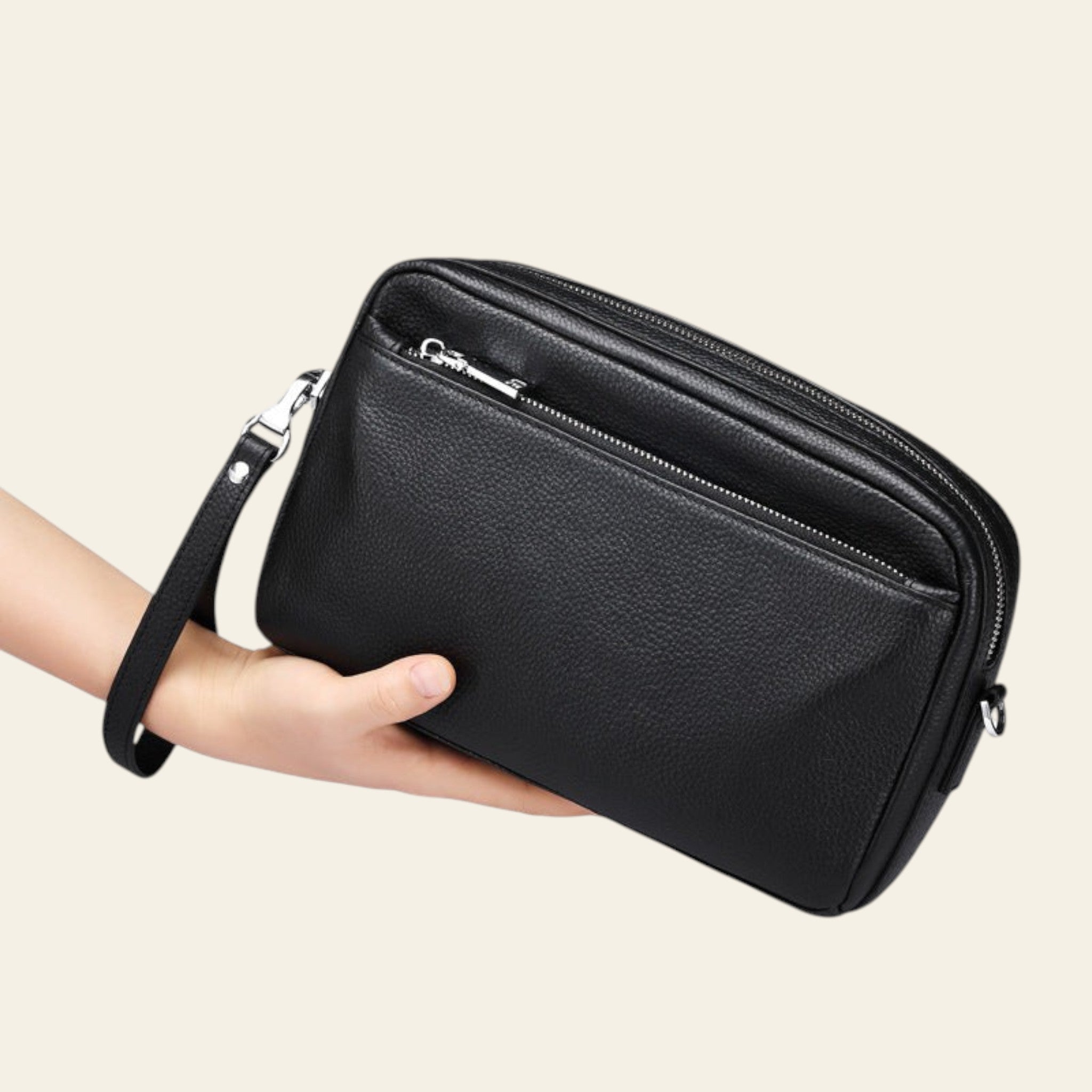 Black leather clutch bag held by a hand on a white background