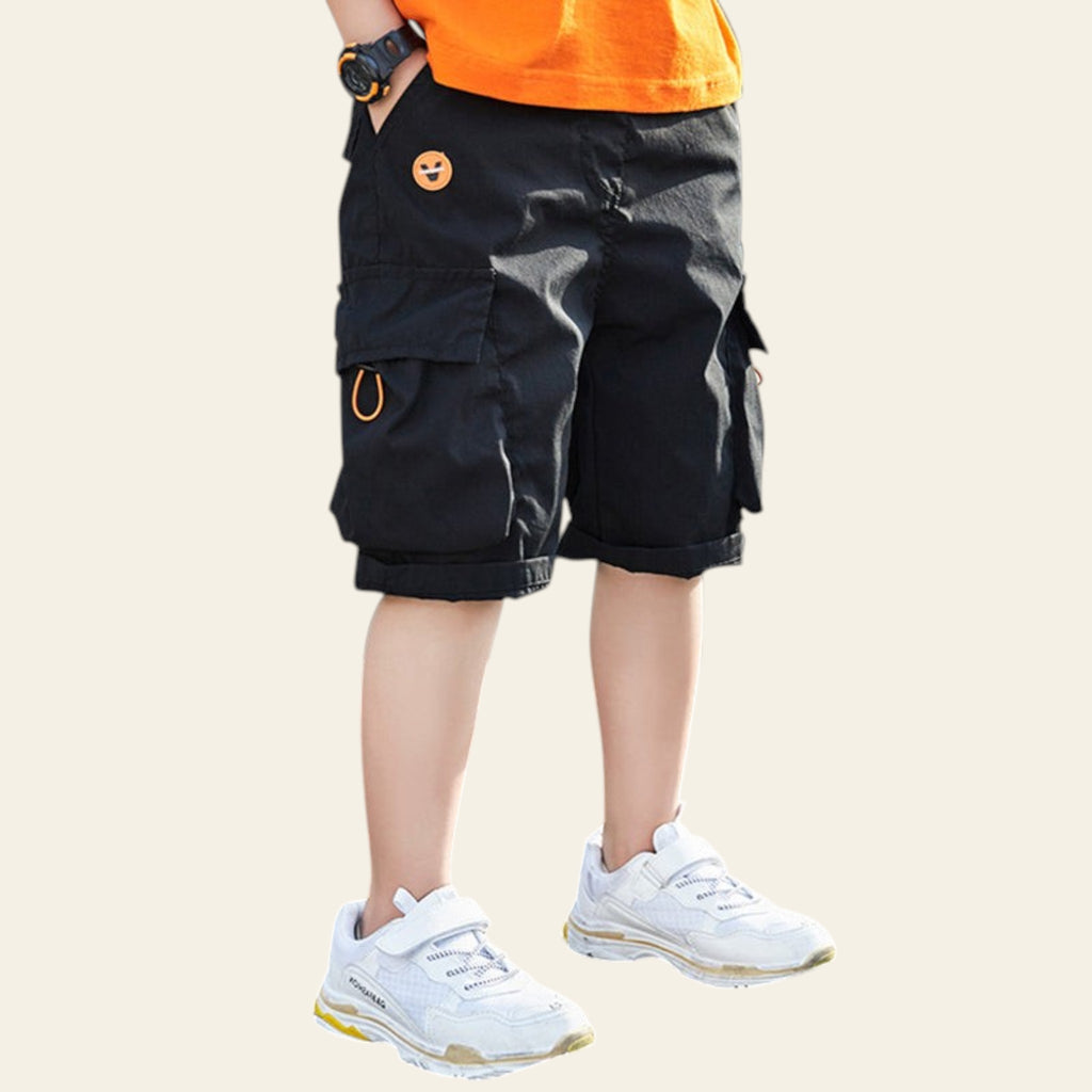 Person wearing black cargo shorts and white sneakers on a plain background