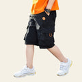 Child wearing black cargo shorts and white sneakers on a street.