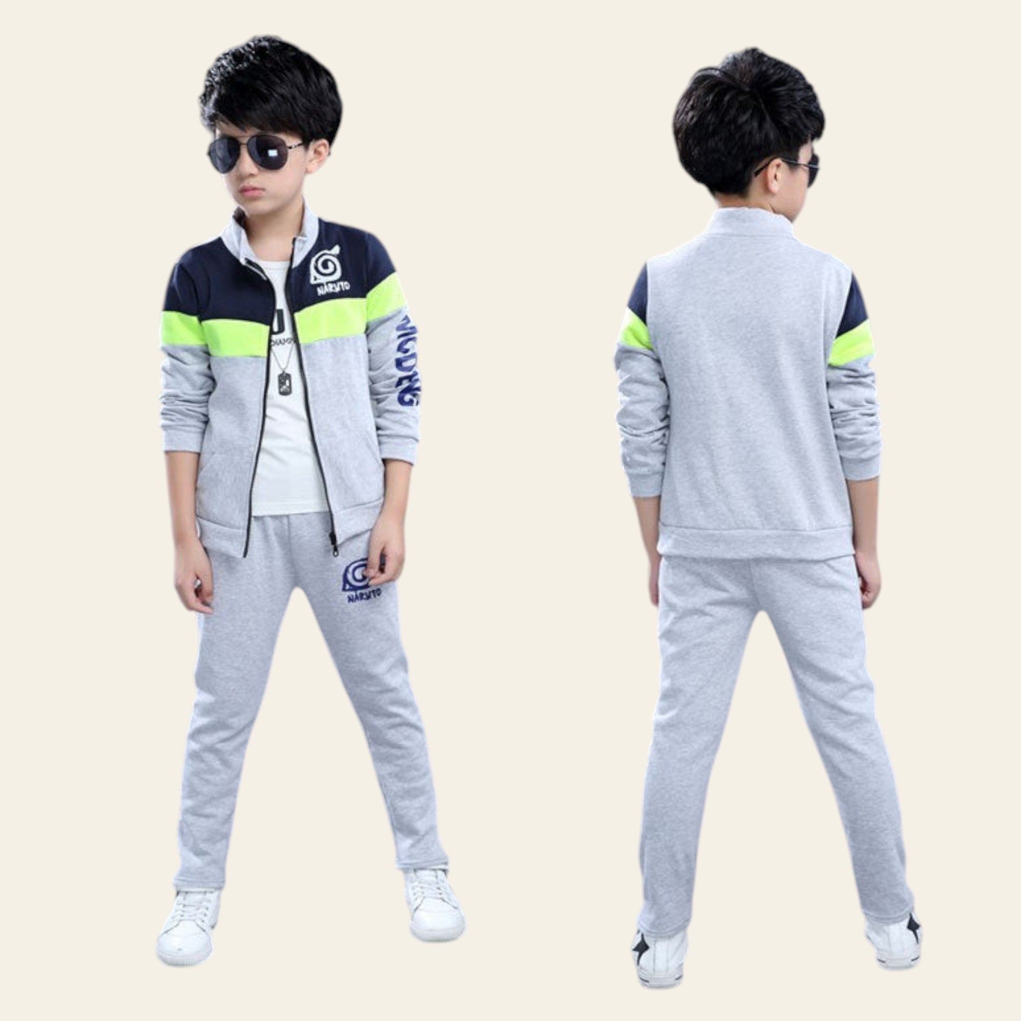 Child wearing a gray and navy tracksuit with green accents, standing against a gray background.