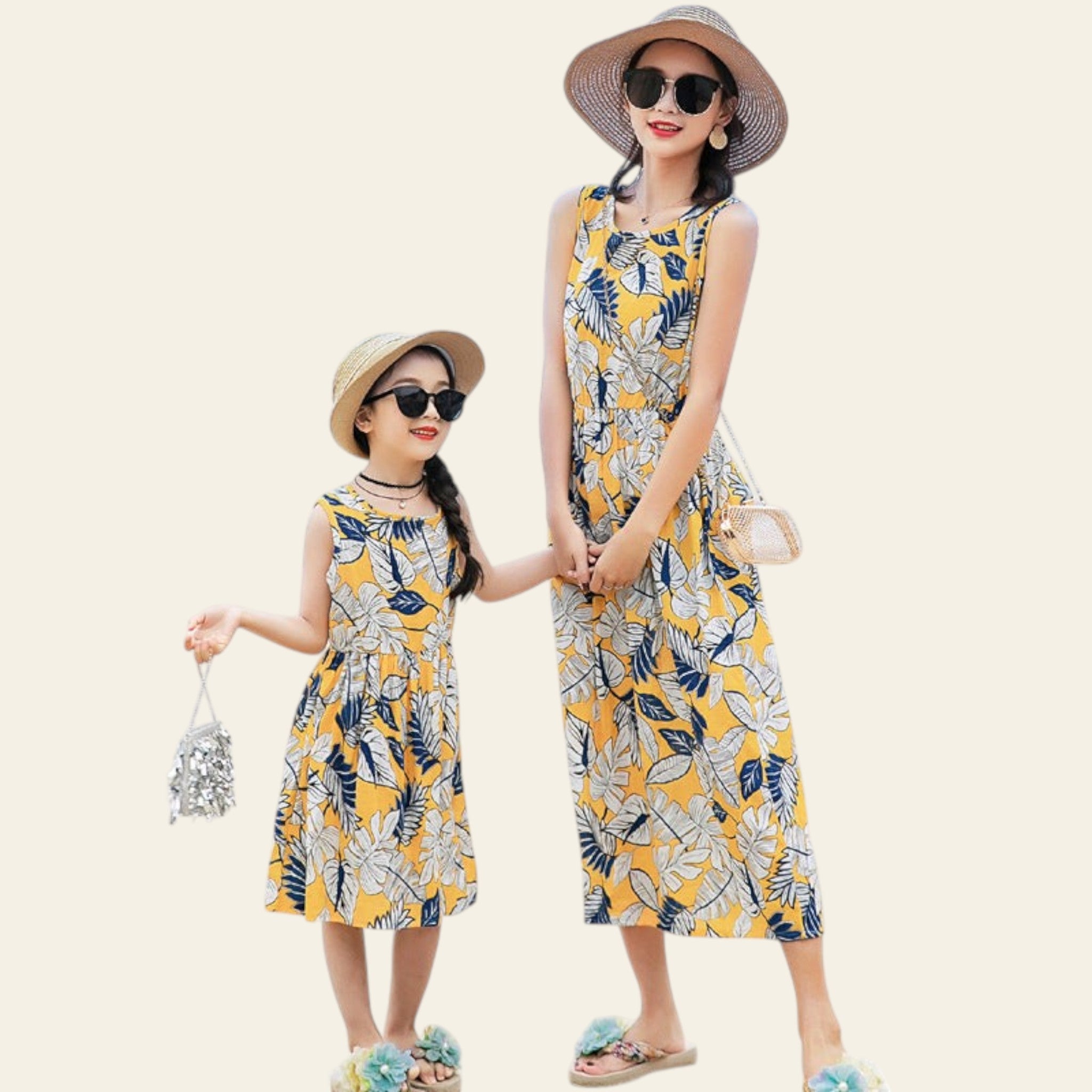 Two women in matching yellow floral dresses standing on a beach.