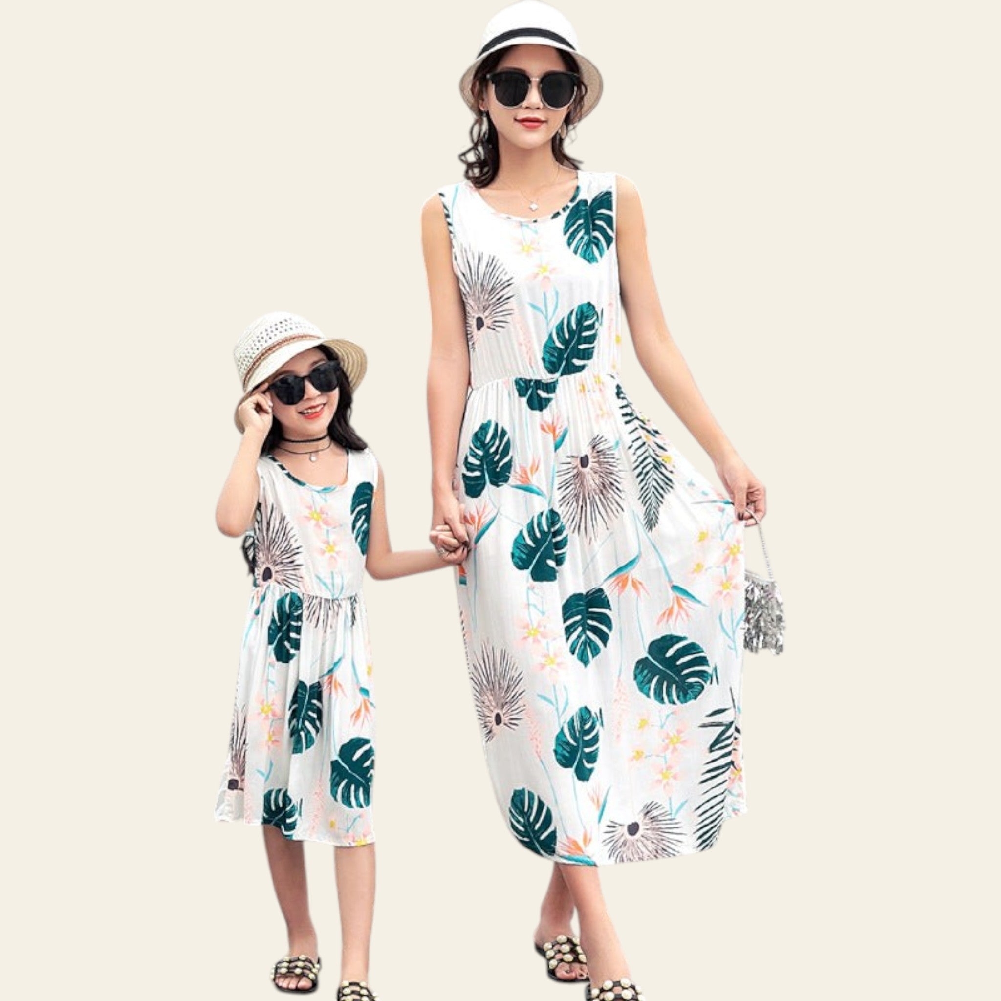 Mother and daughter wearing matching leaf-patterned dresses by a poolside.