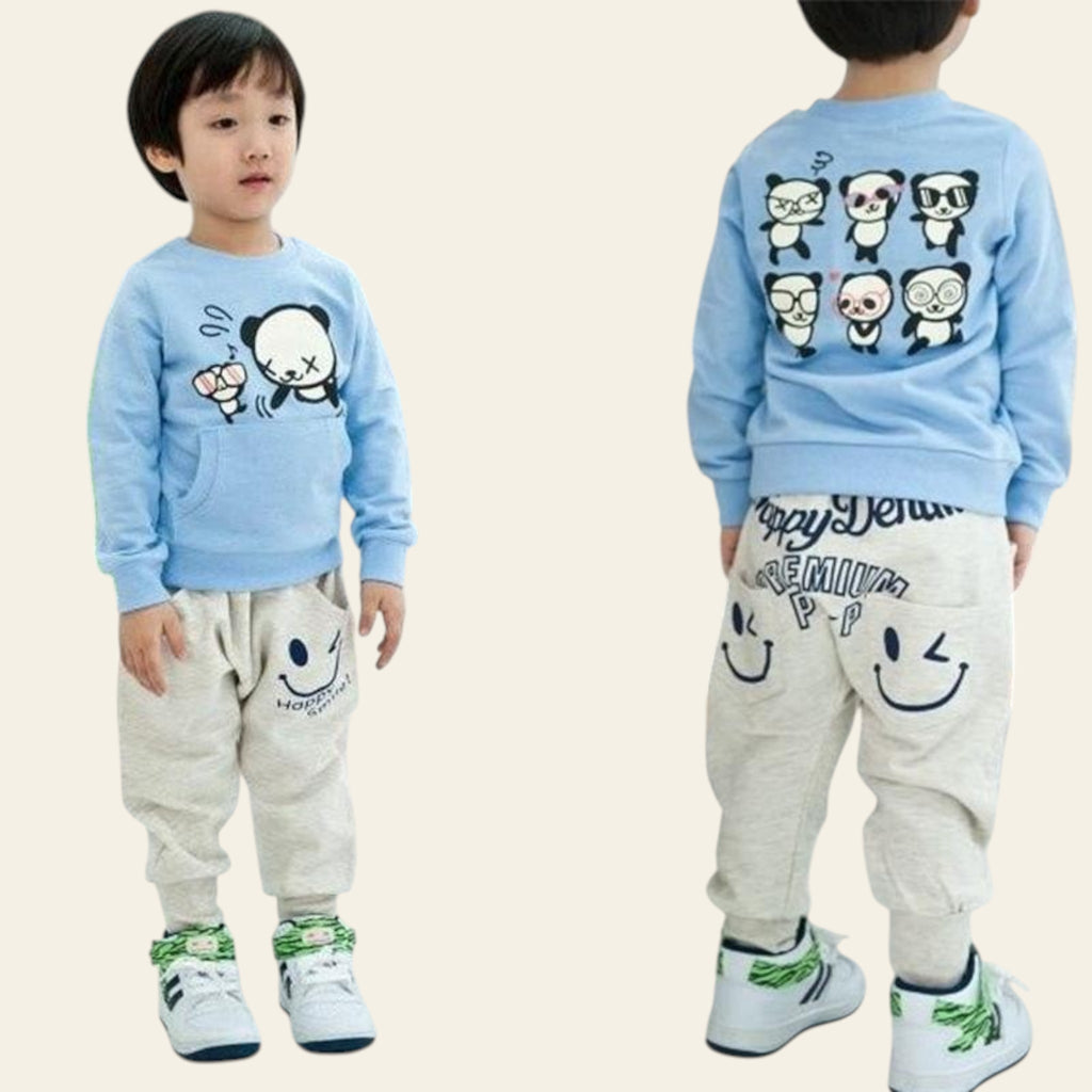 Child wearing a blue sweater with panda designs and beige pants with smiley face prints.