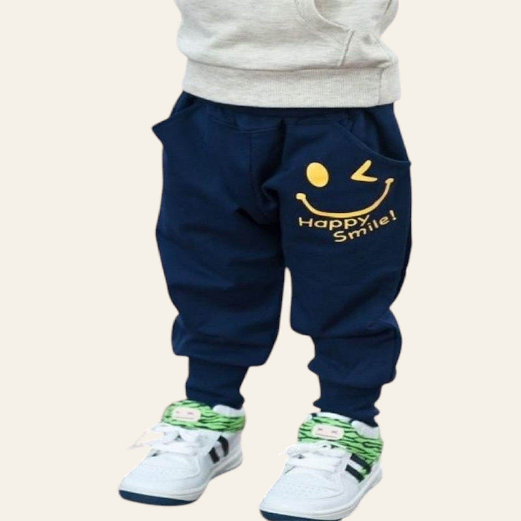 Navy blue pants with smiley face design and 'Happy Smile!' text worn by a child, standing on a wooden floor.