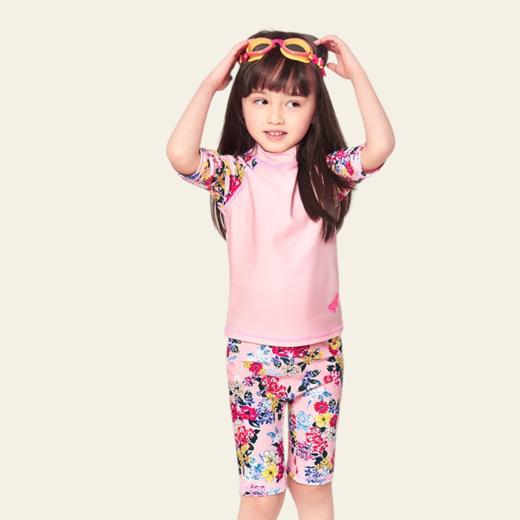 Child wearing a pink floral outfit with sunglasses on a white background