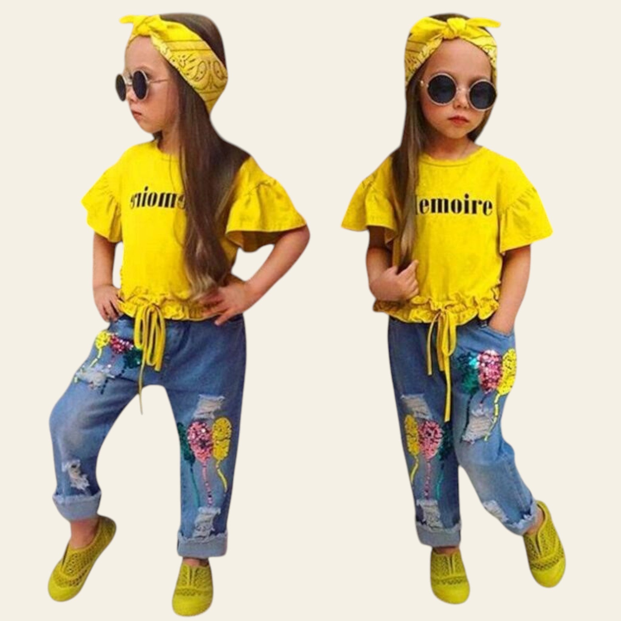 Two children in matching yellow tops and blue jeans with floral accents, standing against a decorative wall.