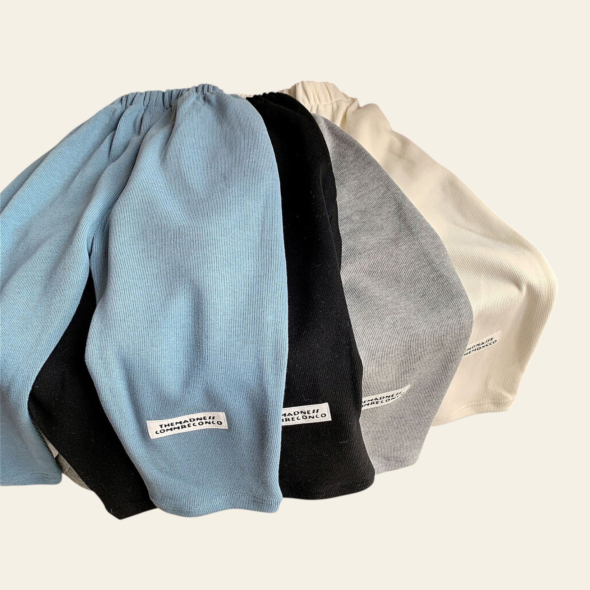Four folded sweaters in blue, black, gray, and white on a surface.