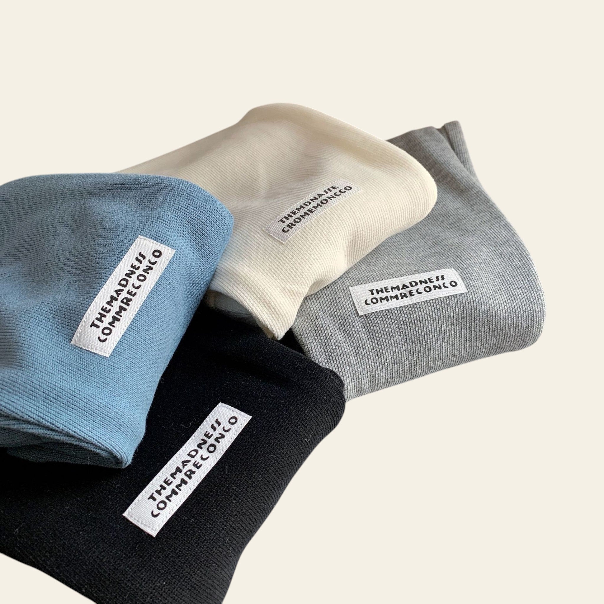 Four folded socks in blue, white, black, and gray with visible brand labels on a light surface.
