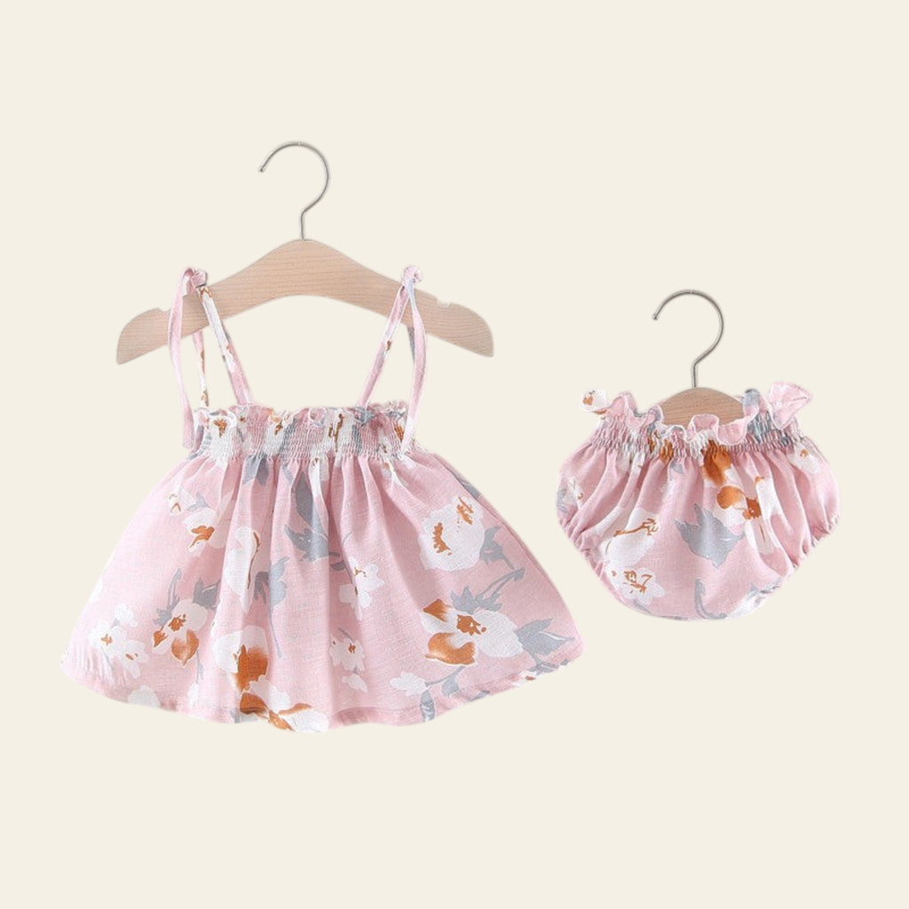 Baby dress and bloomers set with animal print on hangers against a white background