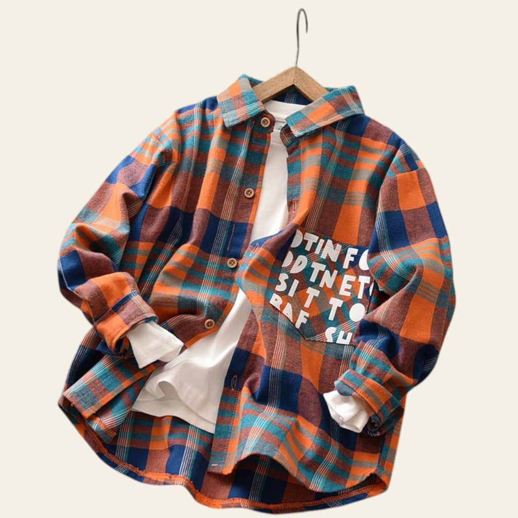 Plaid shirt with text on a wooden surface with toys and flowers in the background