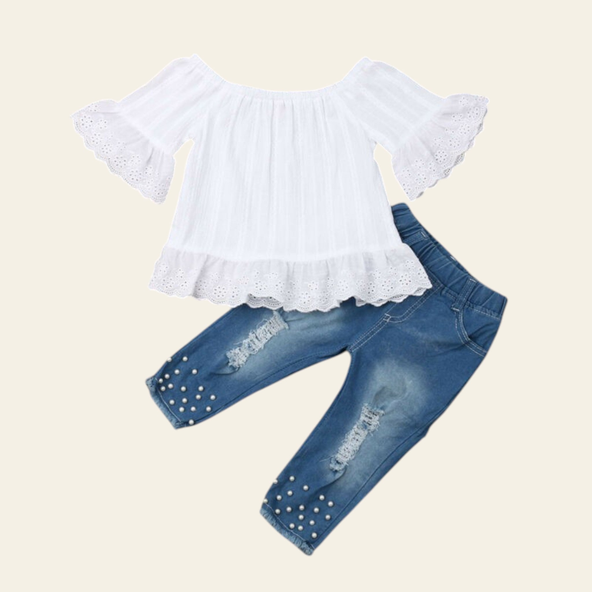 White lace top and blue jeans with pearl details on a wooden surface.