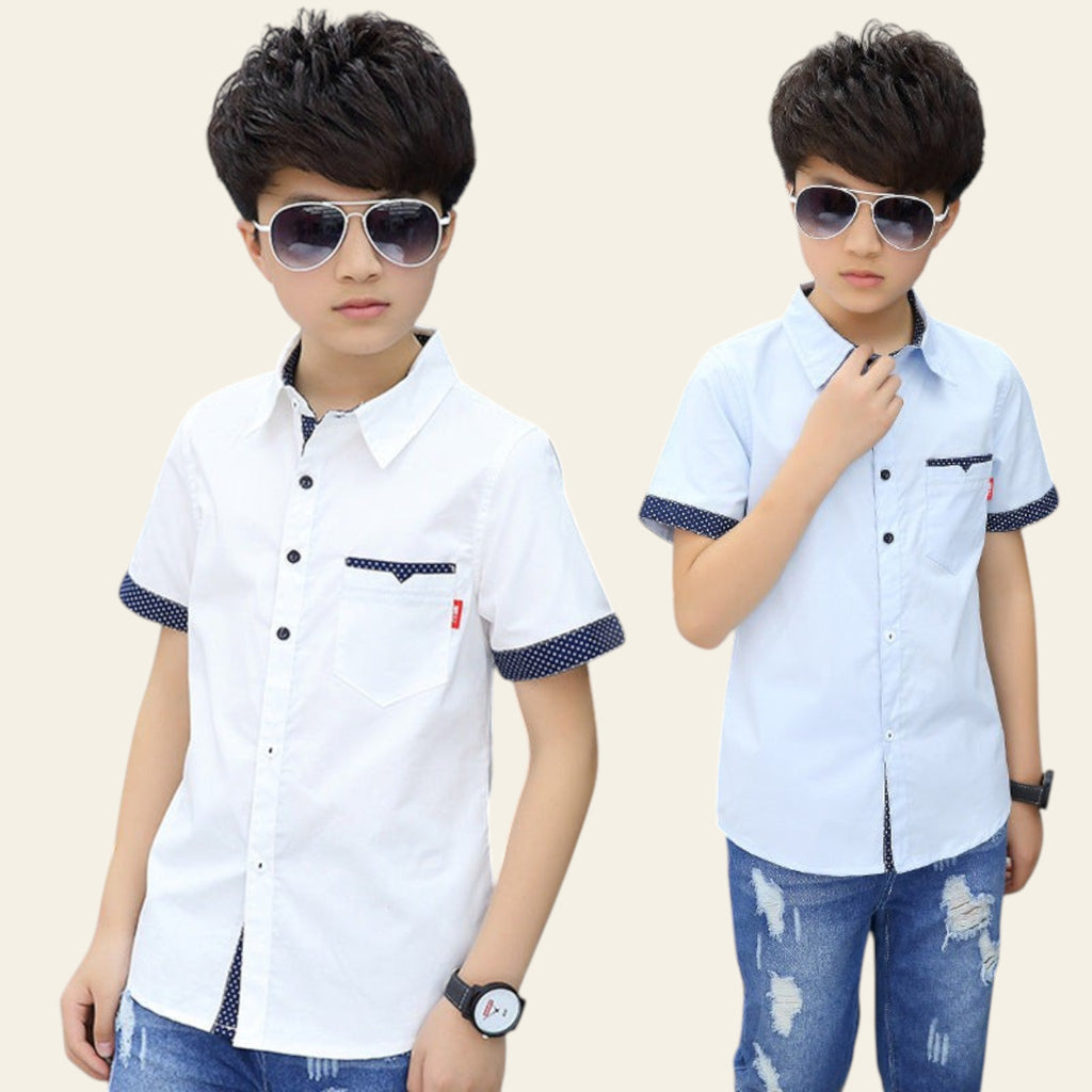 Two children wearing matching white shirts with blue accents and jeans, standing in front of a grid-patterned wall.