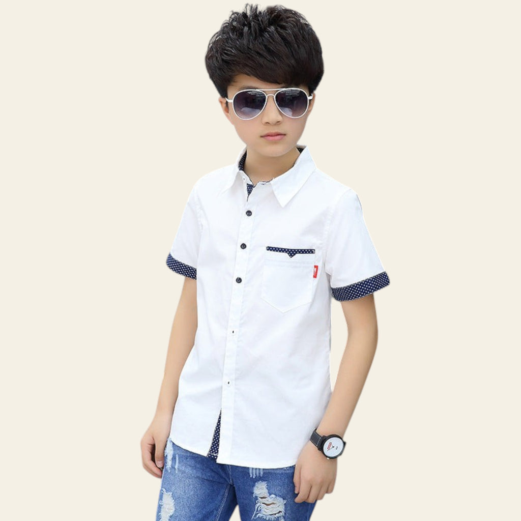 Child wearing a white short-sleeve shirt with blue accents and sunglasses, standing outdoors.