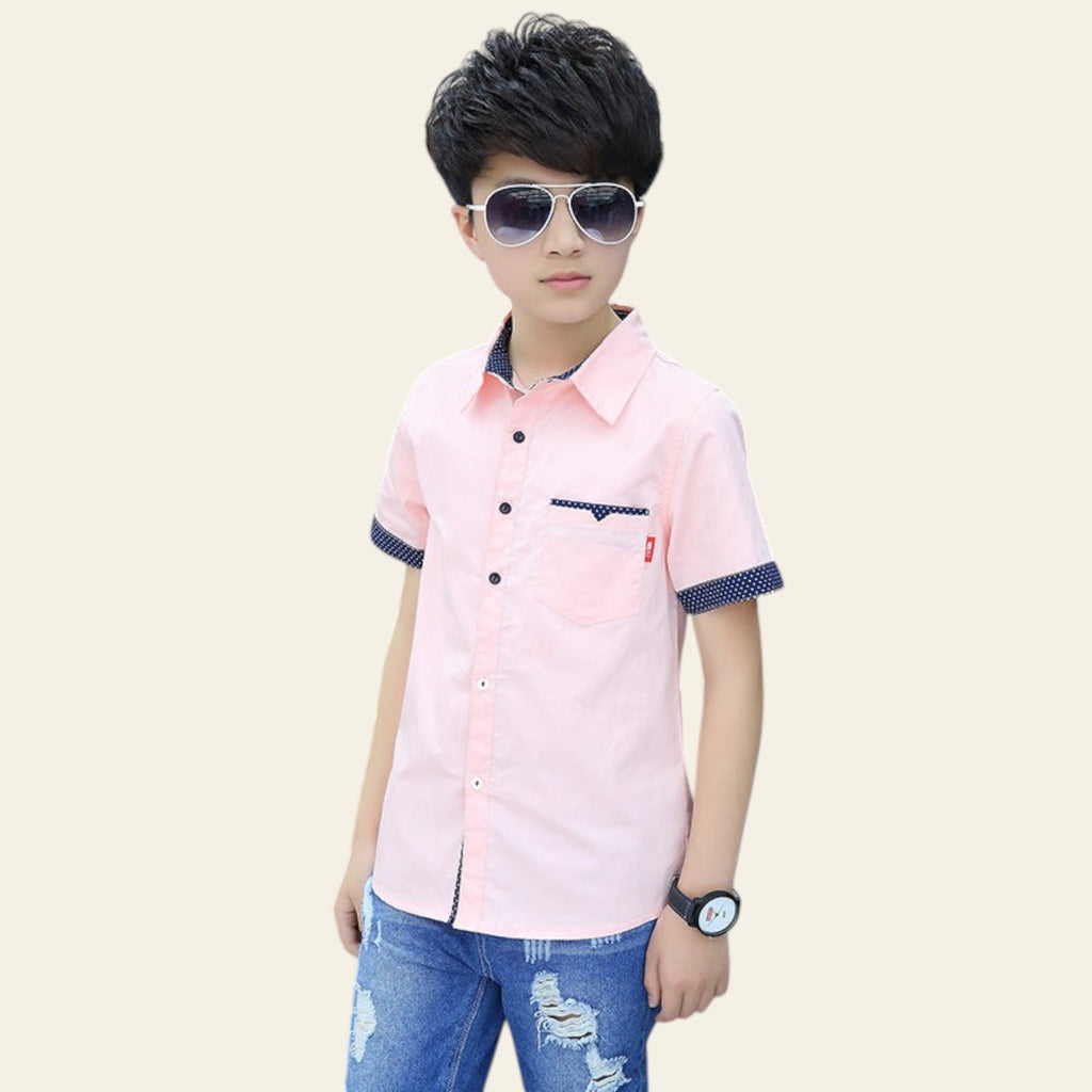 Child wearing a pink shirt with navy accents and blue jeans, standing outdoors.