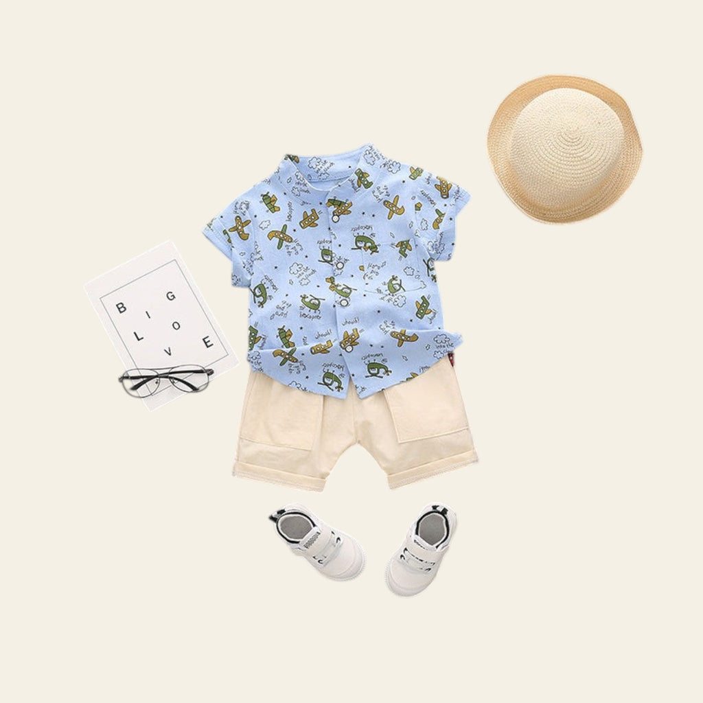 Children's outfit with blue shirt, beige shorts, shoes, and a hat on a gray background