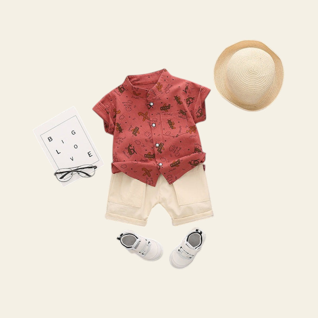 Children's outfit with red shirt, beige shorts, white shoes, and straw hat on a gray background