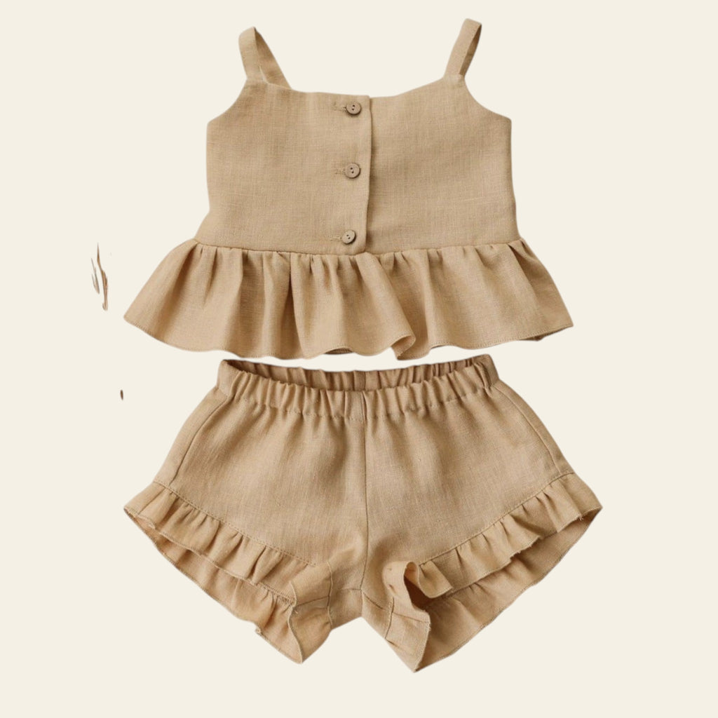 Beige ruffled top and shorts set on a light background with dried flowers.
