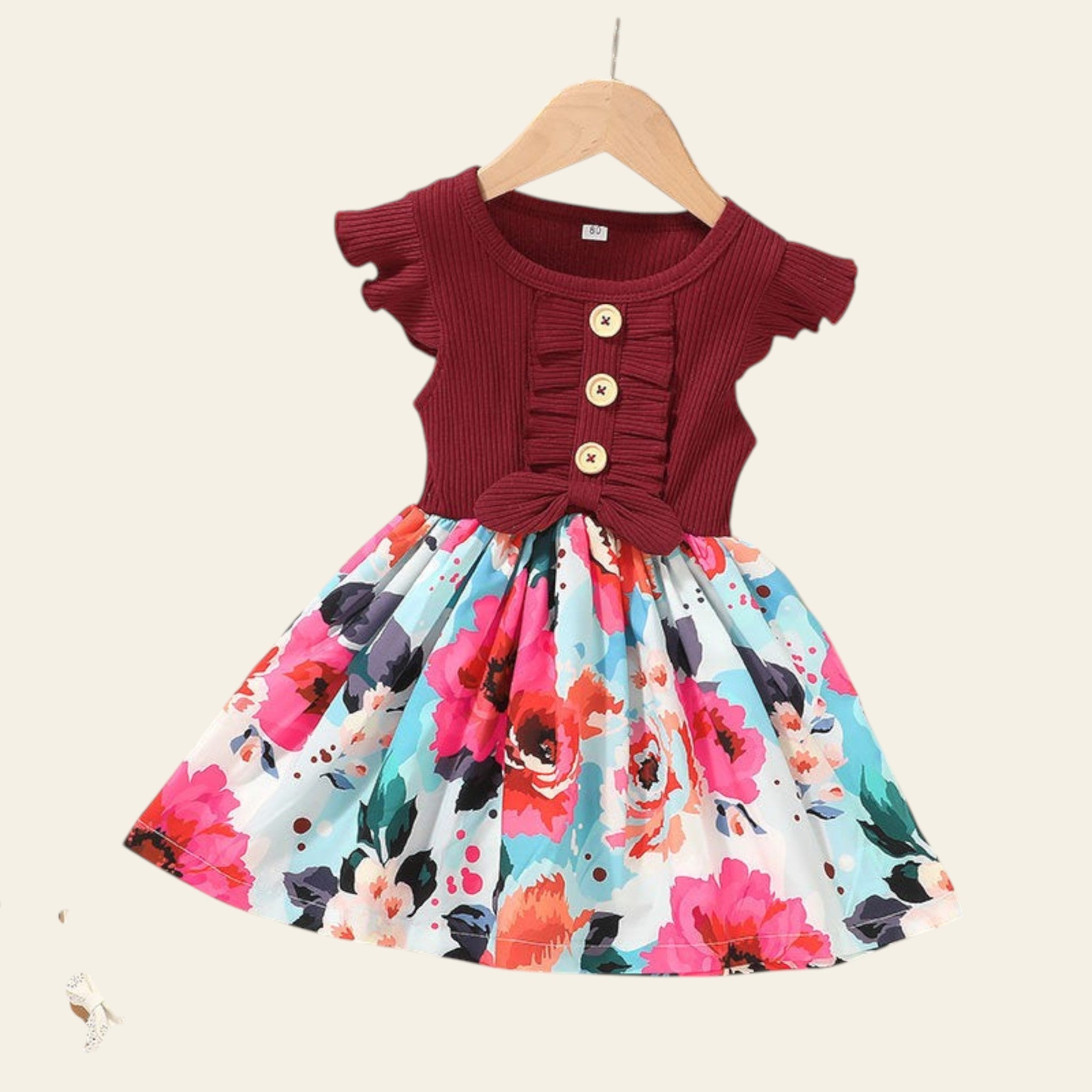 Children's dress with floral skirt and ruffled top on a beige background