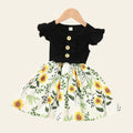 Black top with button details and sunflower print skirt on a beige background
