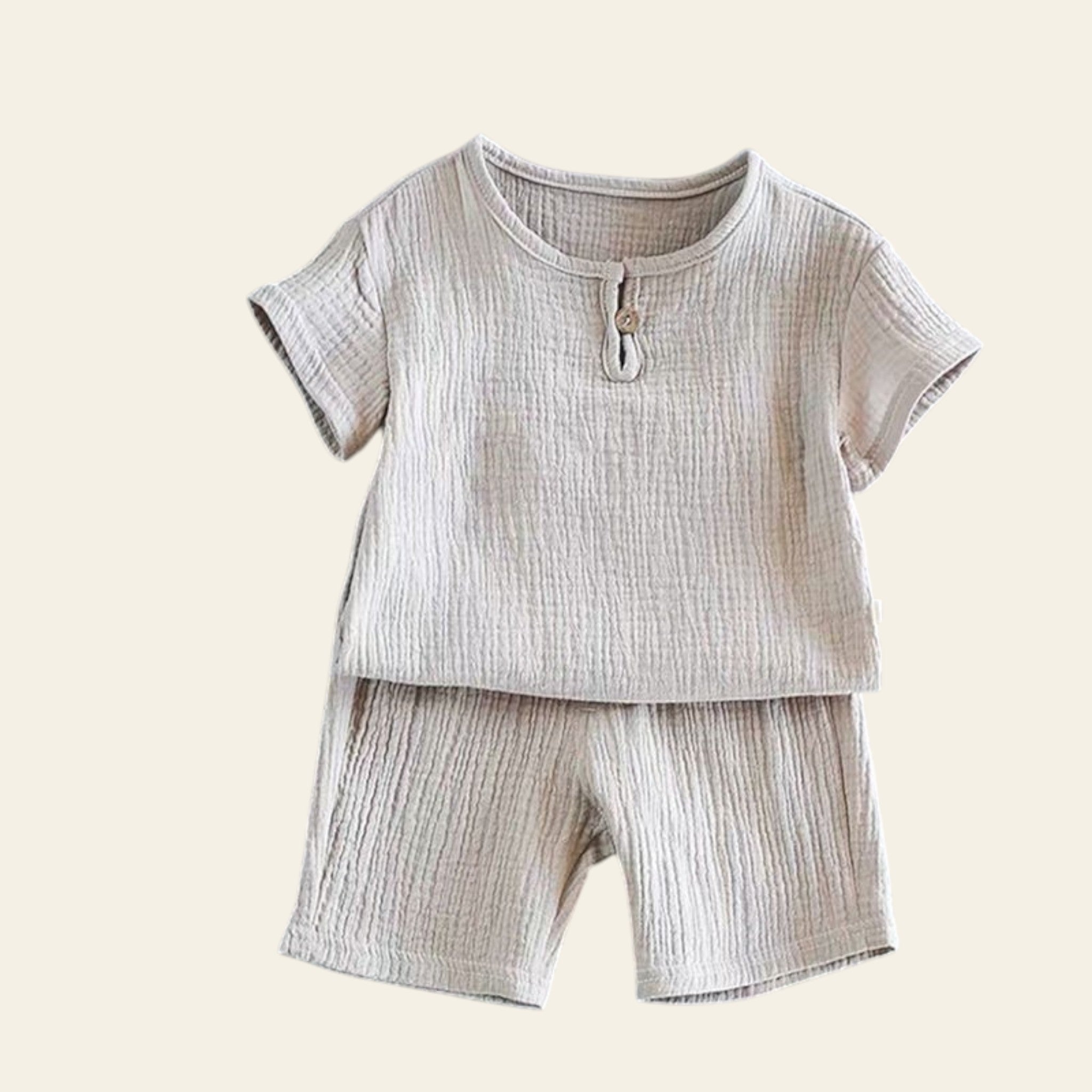 Children's beige outfit with shirt and shorts on a gray background