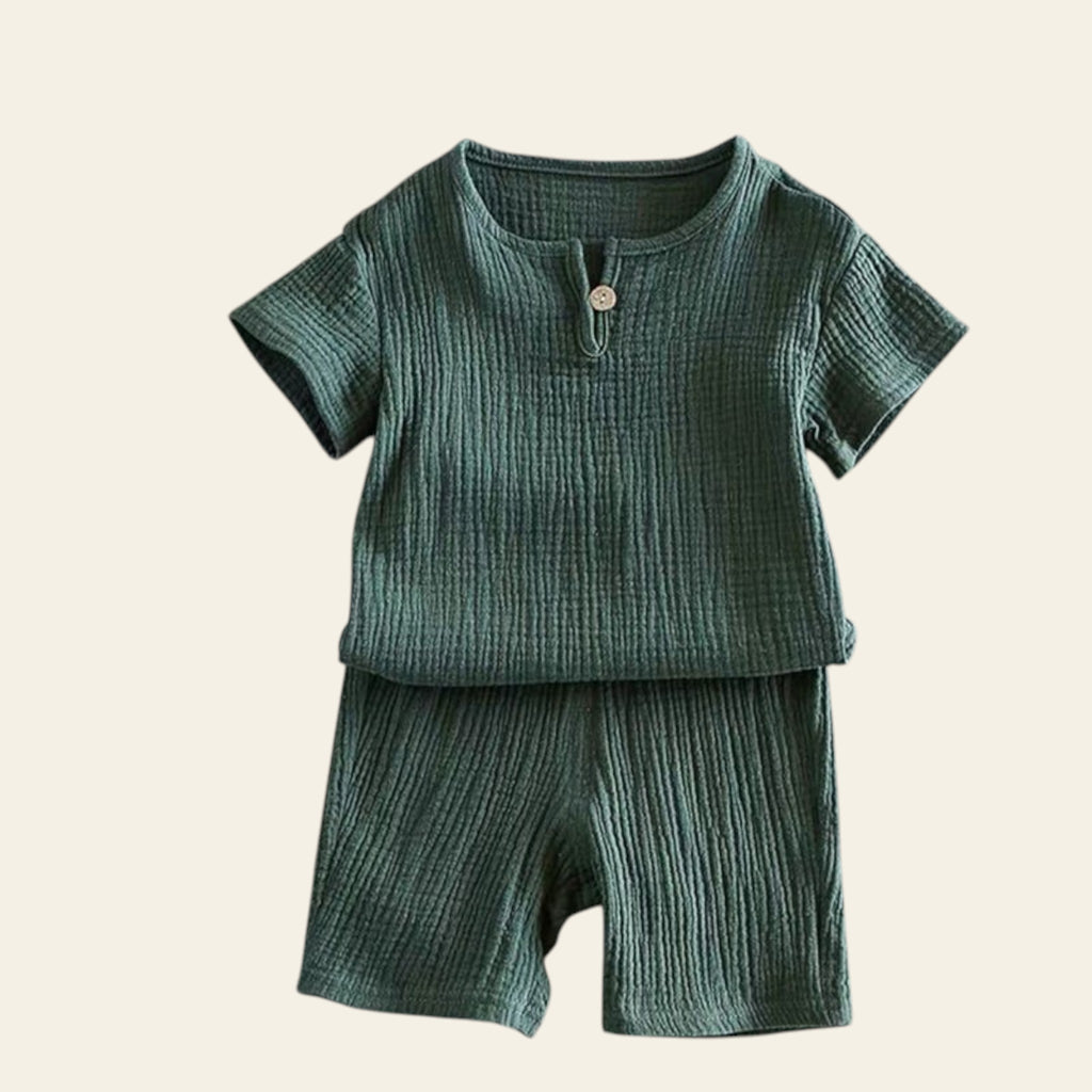 Green baby outfit with shirt and shorts on a light gray background
