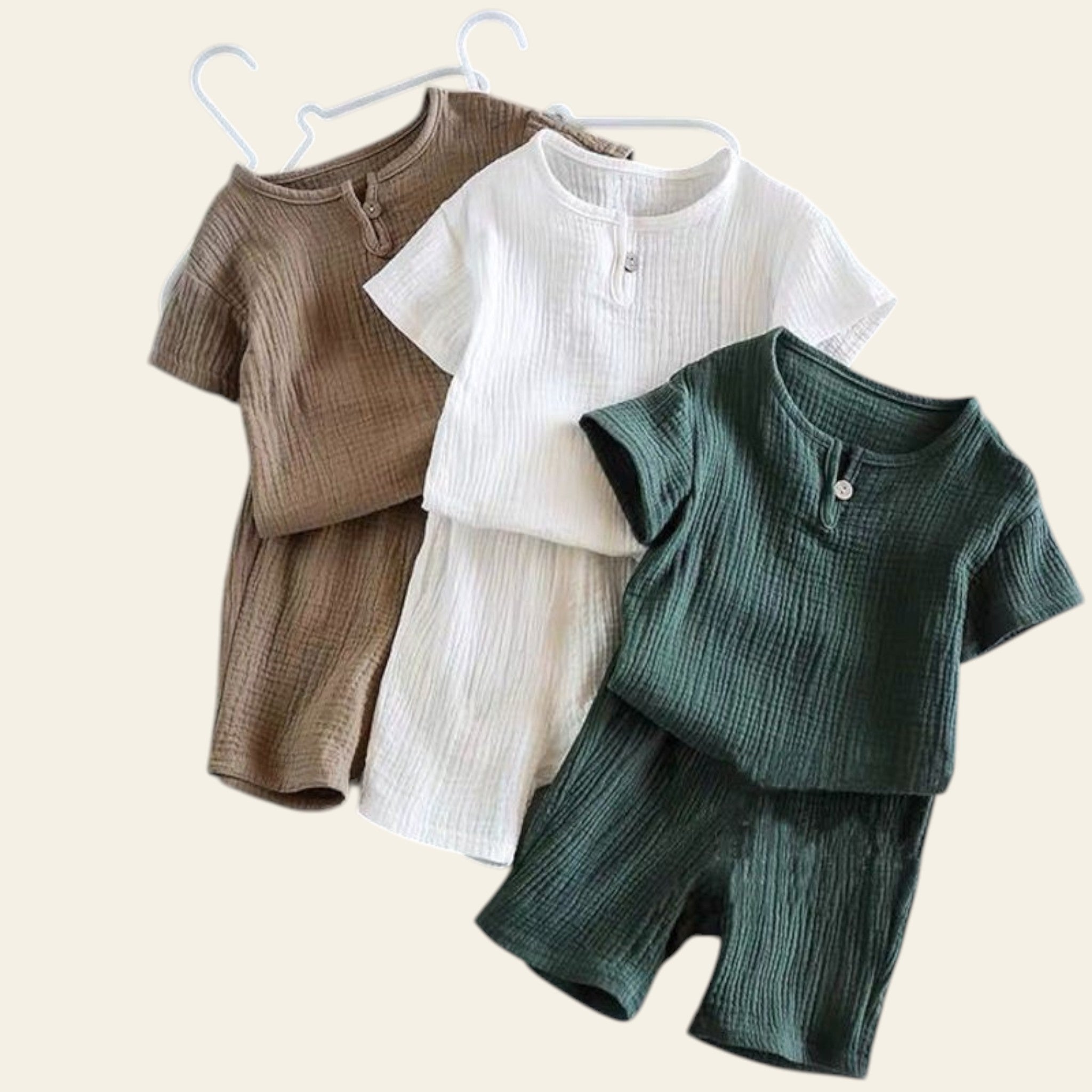 Three children's outfits in brown, white, and green on a gray background.