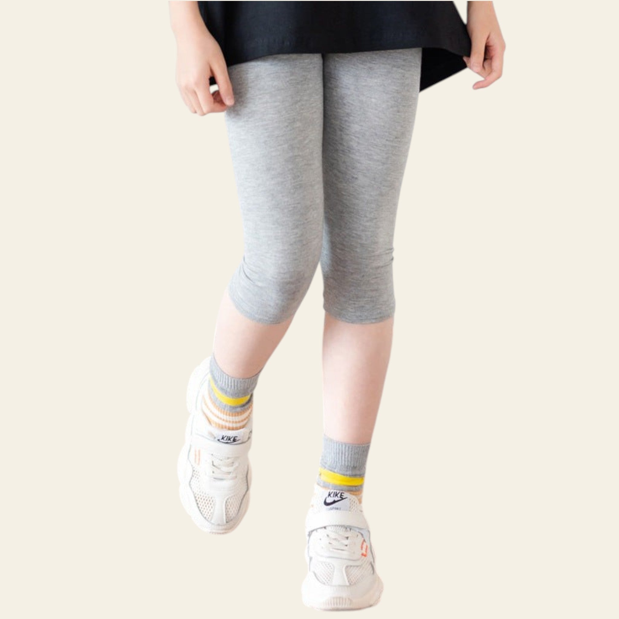 Person wearing gray leggings and white sneakers on a wooden floor.