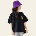 Person wearing a black t-shirt with a colorful logo and a purple bucket hat against a white background