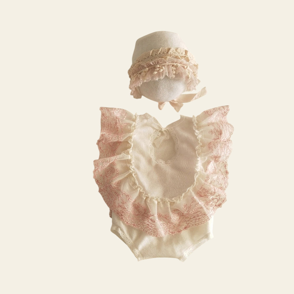 Baby outfit with lace details on a beige background
