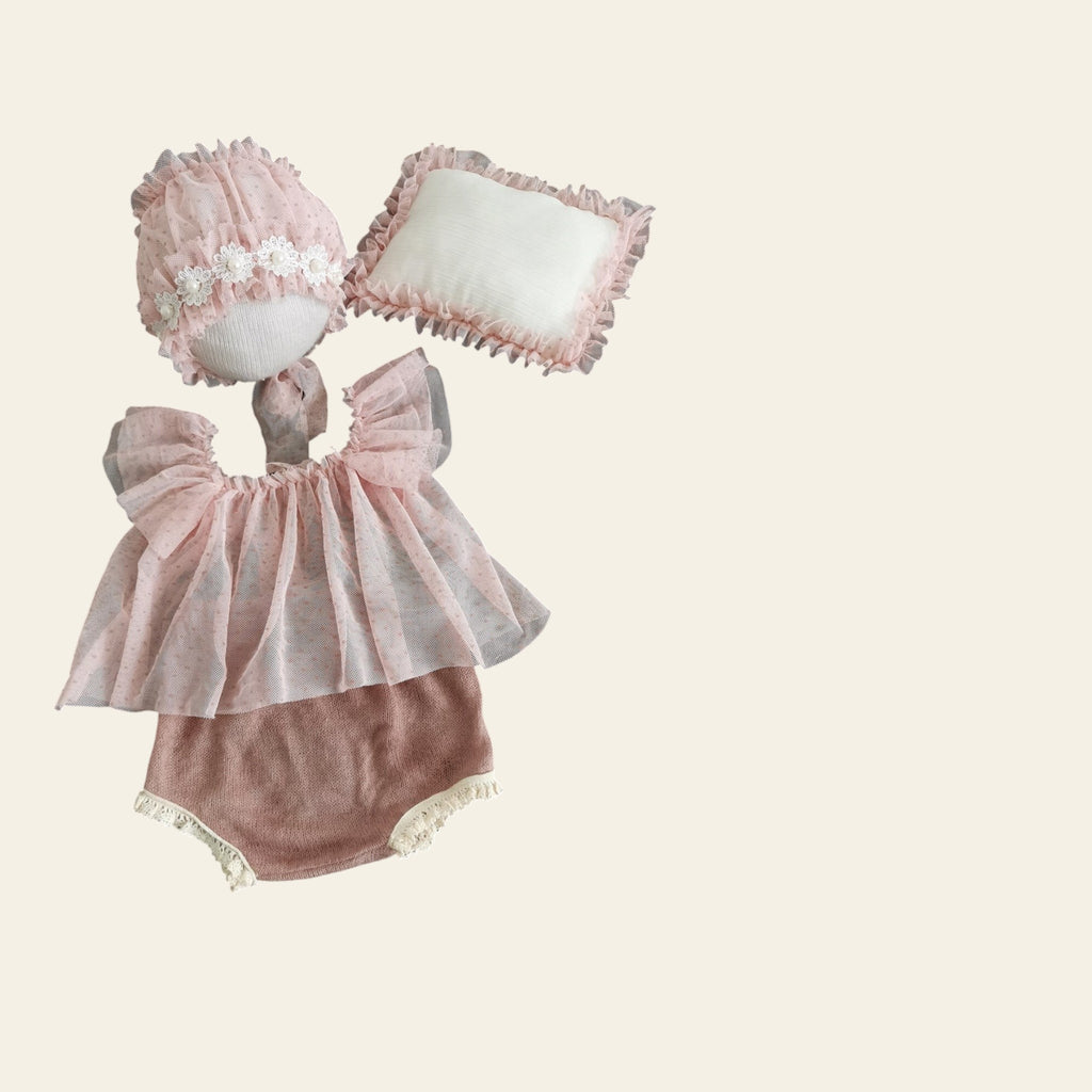 Baby outfit with pink dress and hat on a textured surface