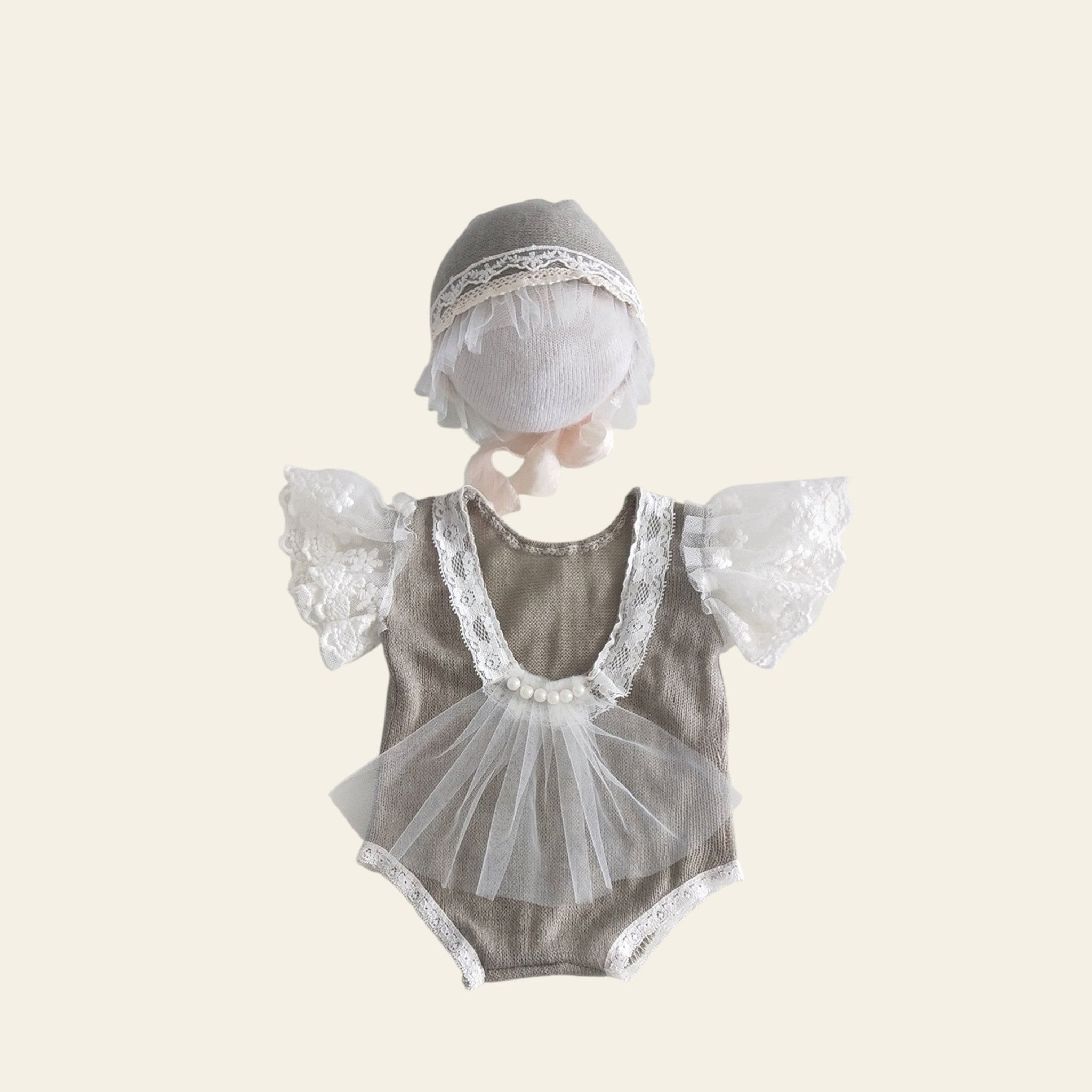 Baby romper with lace details and matching bonnet on a light gray background