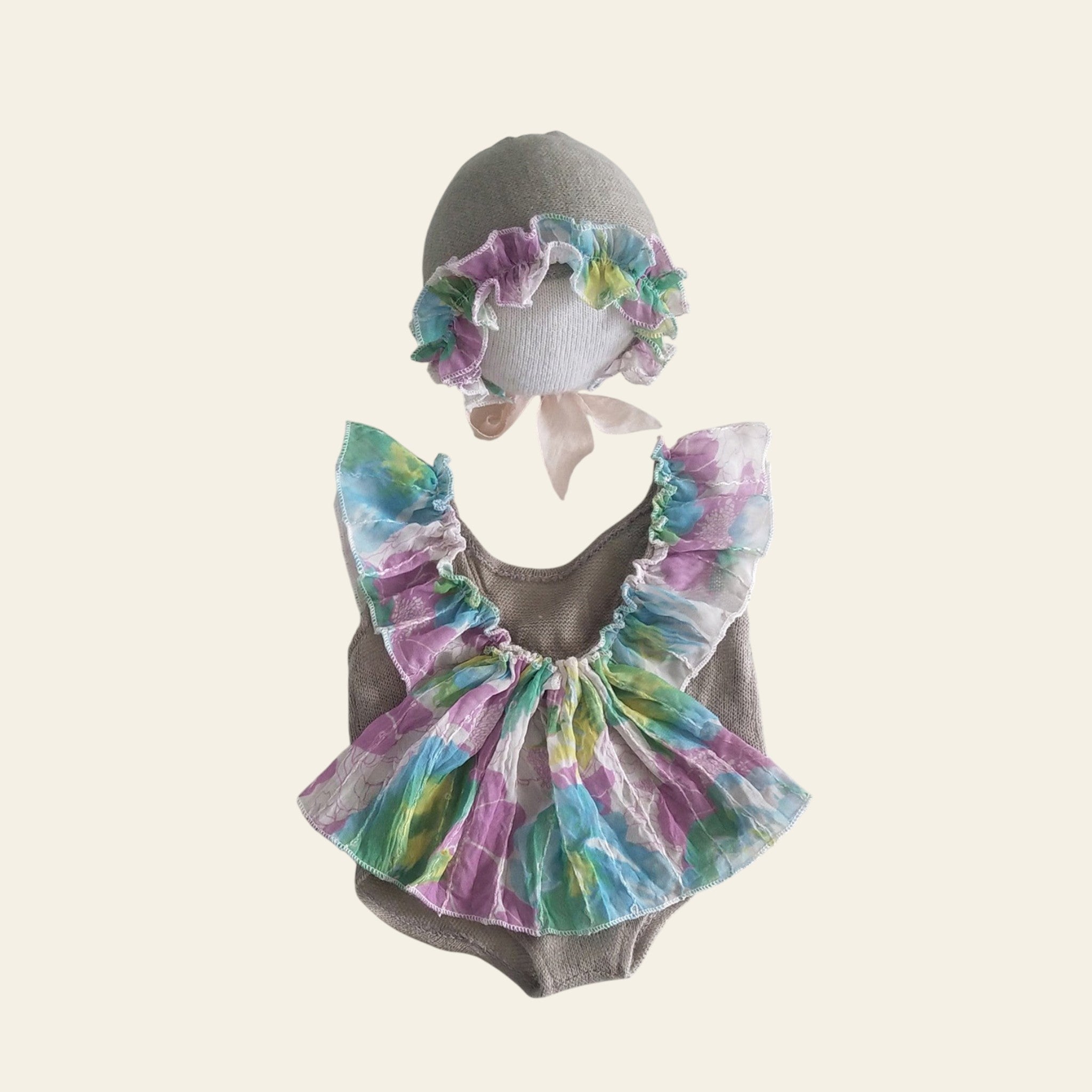 Baby outfit with colorful ruffled top and matching headband on a mannequin against a white background.