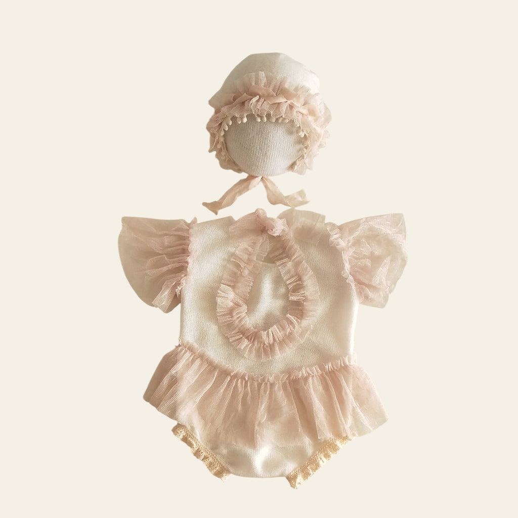Baby outfit set with bonnet and romper on a light background