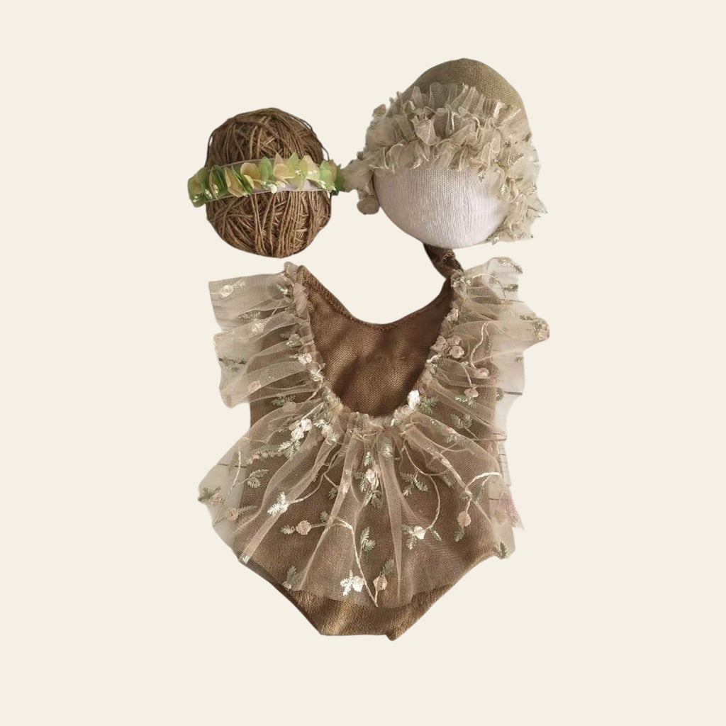 Mannequin head with decorative headband and sheer outfit on a wooden surface with flowers.