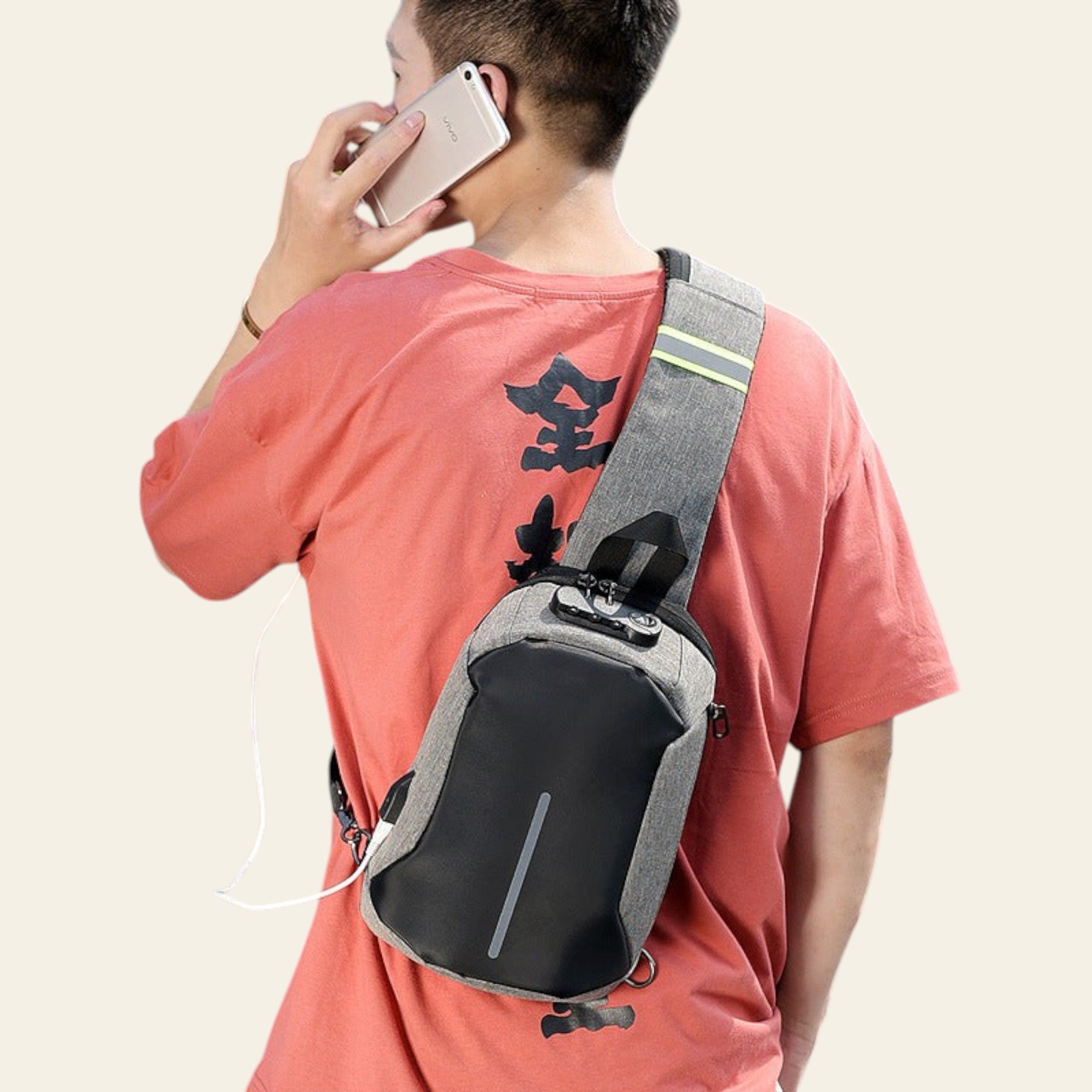 Person wearing a gray and black sling bag while talking on a phone outdoors.