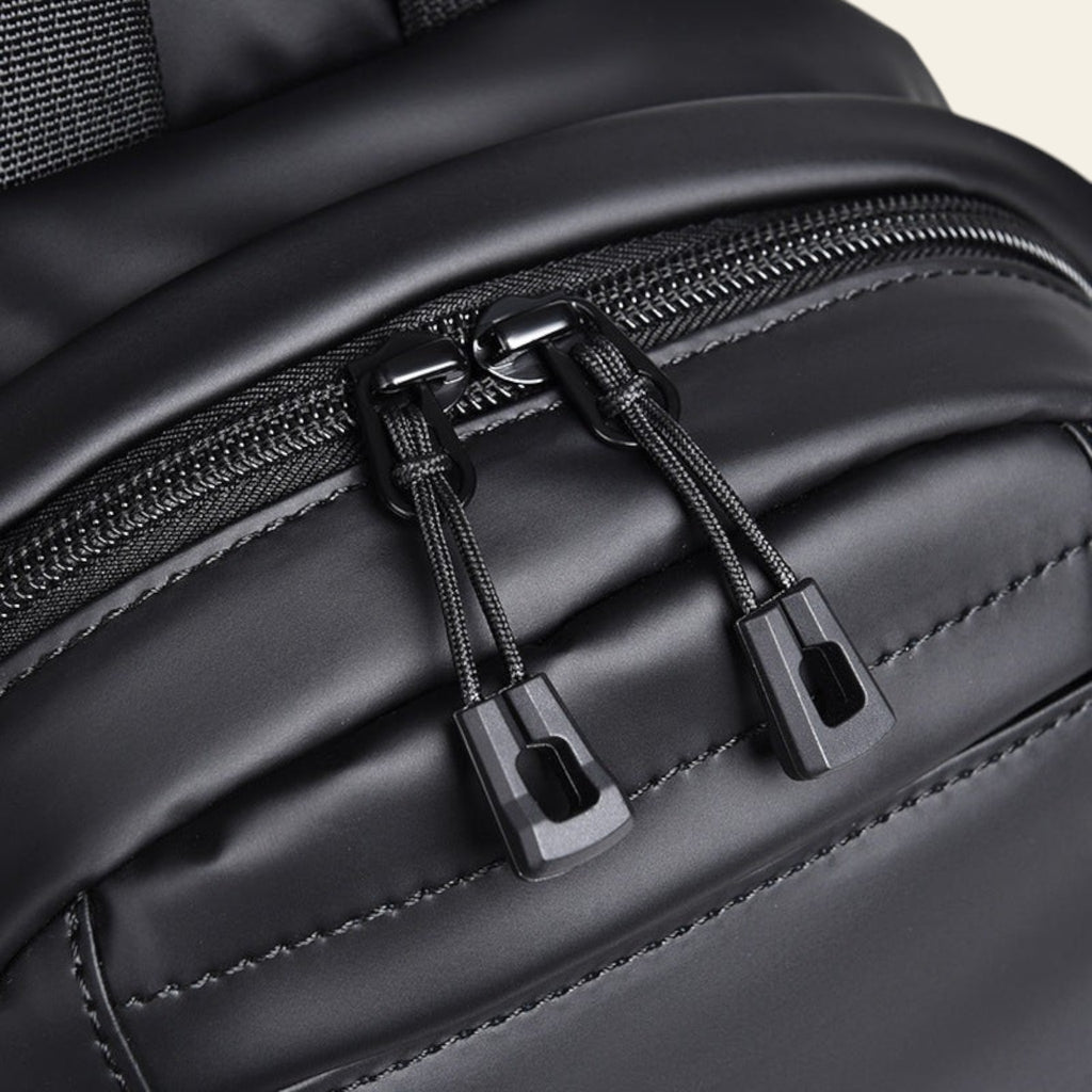 Close-up of a black backpack with zippers and stitching details.