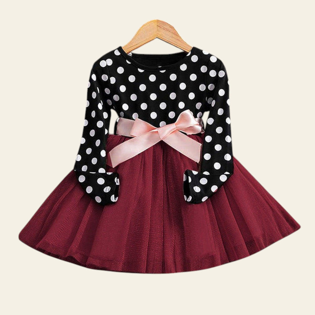 Polka dot dress with a pink bow on a wooden surface