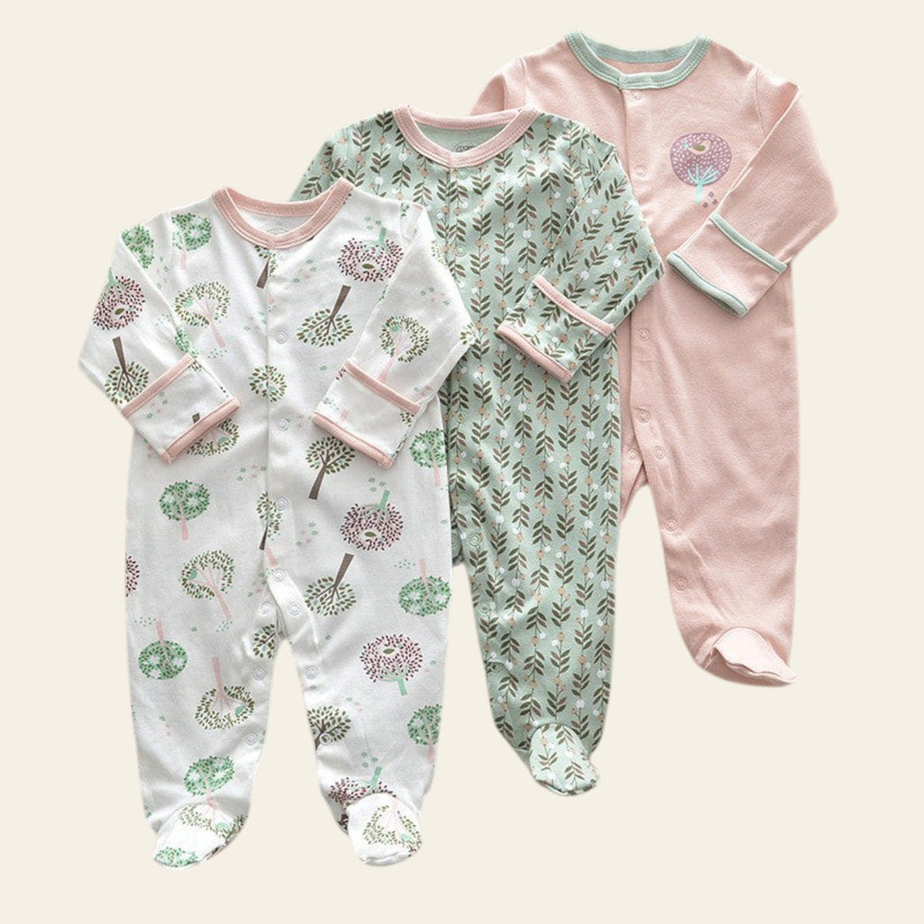 Three baby onesies with different patterns on a beige surface