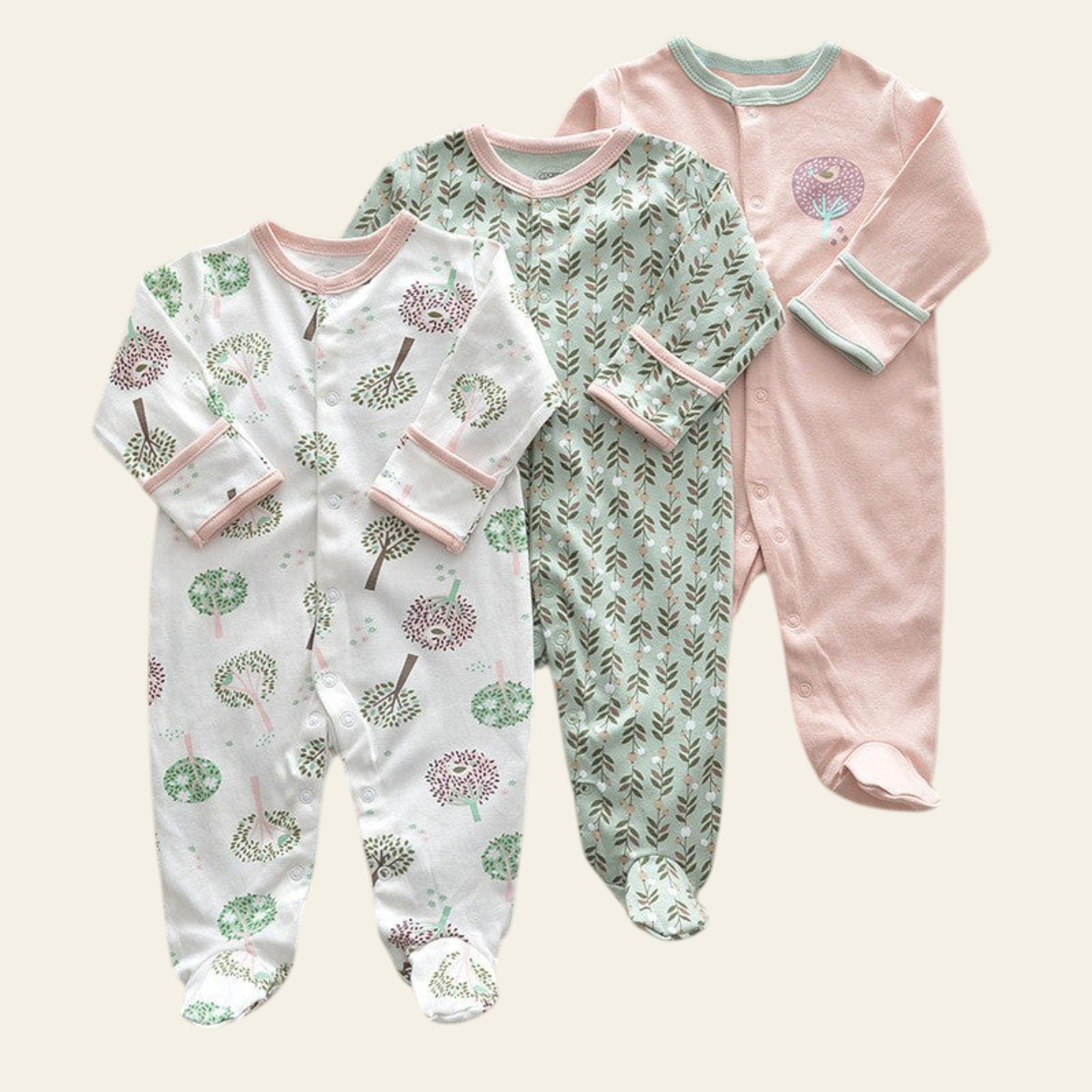 Three baby onesies with different patterns on a beige surface