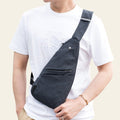 Person wearing a dark gray crossbody bag over one shoulder indoors.