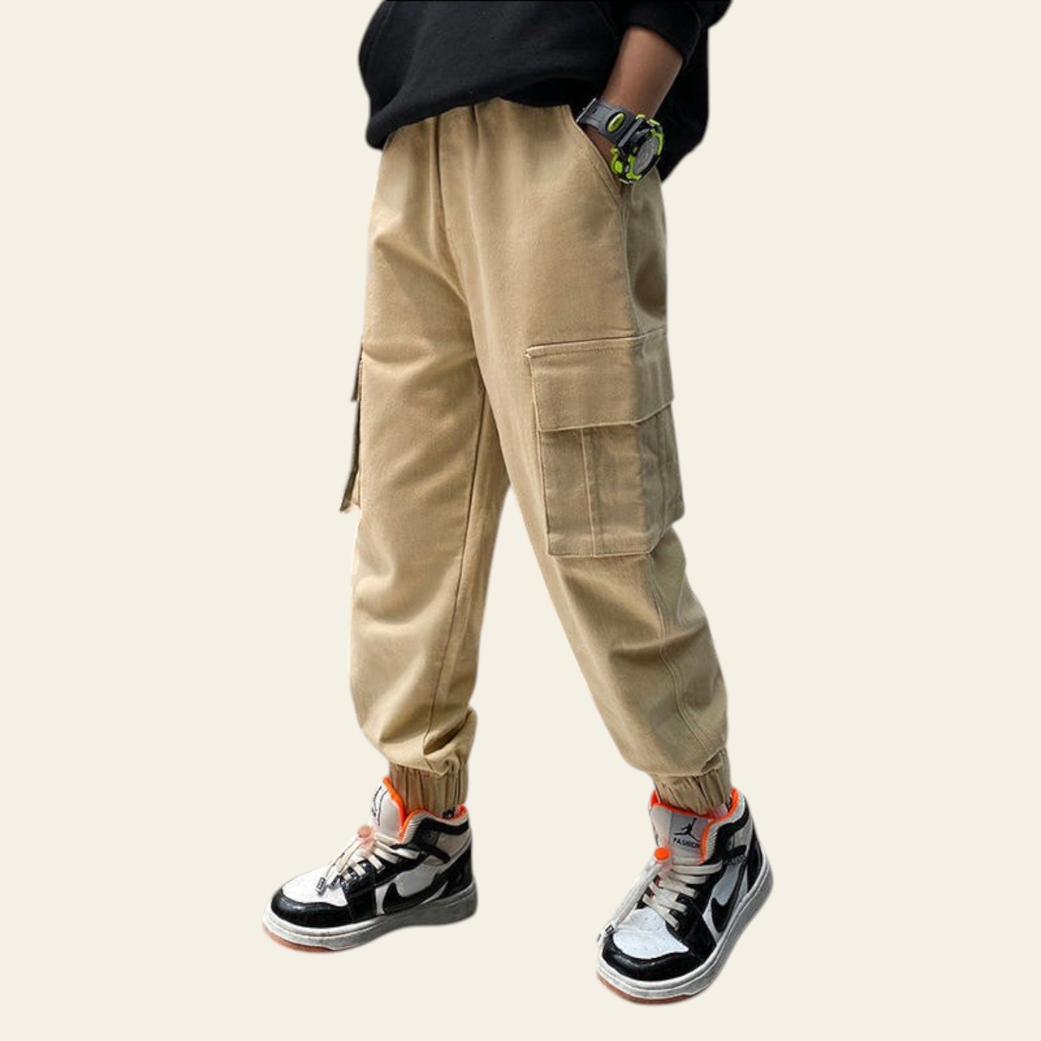 Person wearing beige cargo pants and black sneakers in a modern indoor setting