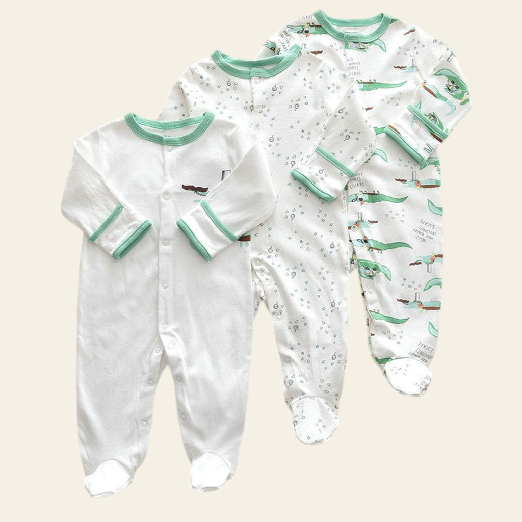Two baby onesies with green trim on a beige surface