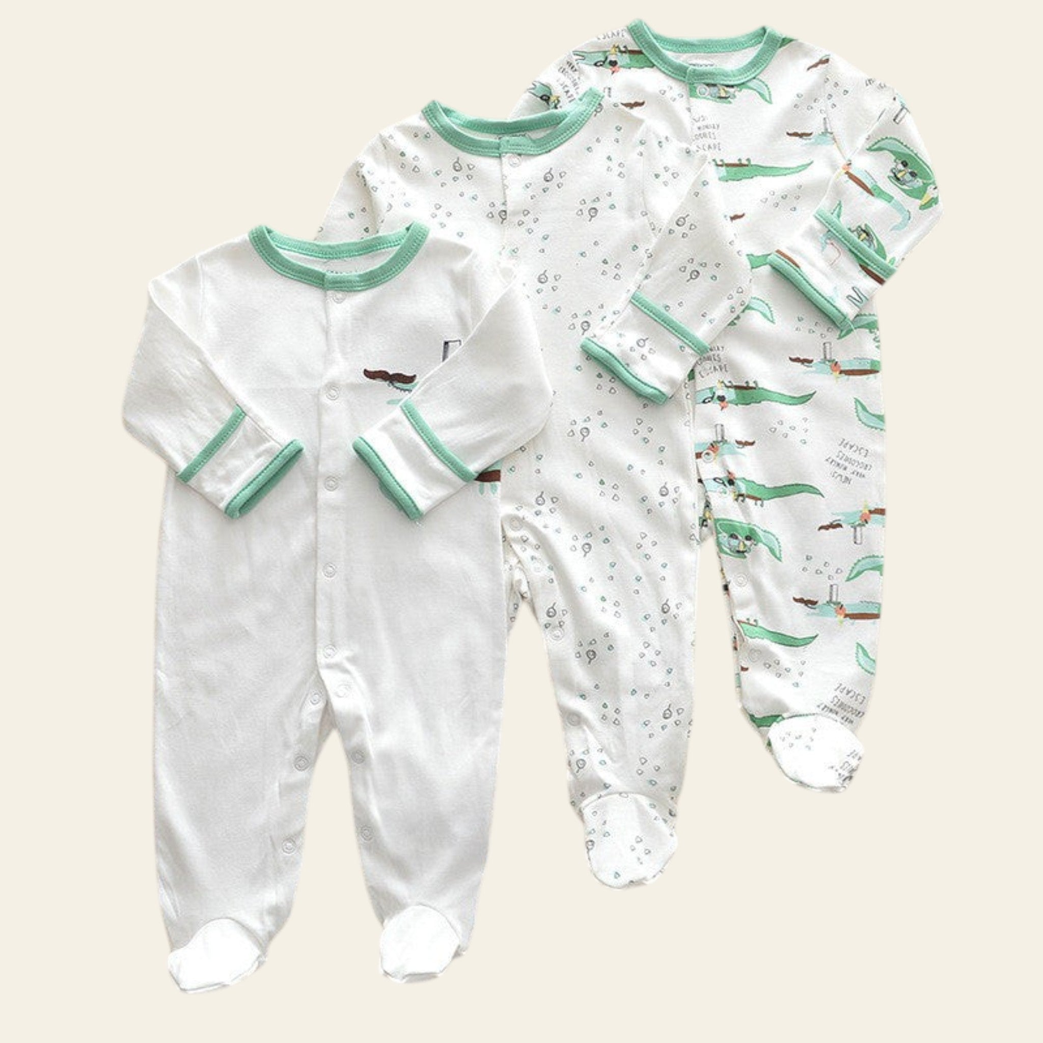 Two baby onesies with green trim on a beige surface