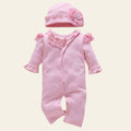 Pink baby romper with matching hat on a beige background