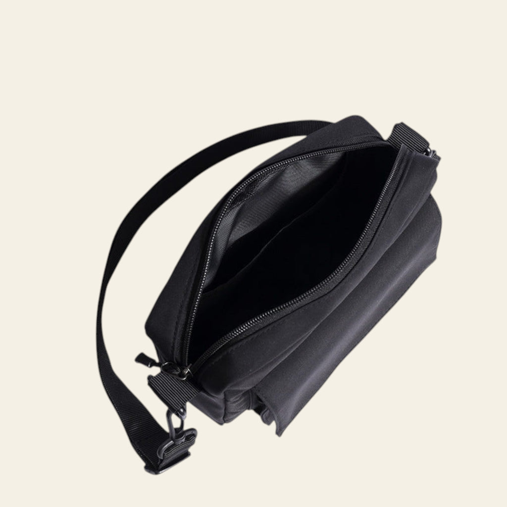 Black crossbody bag with a strap on a white background