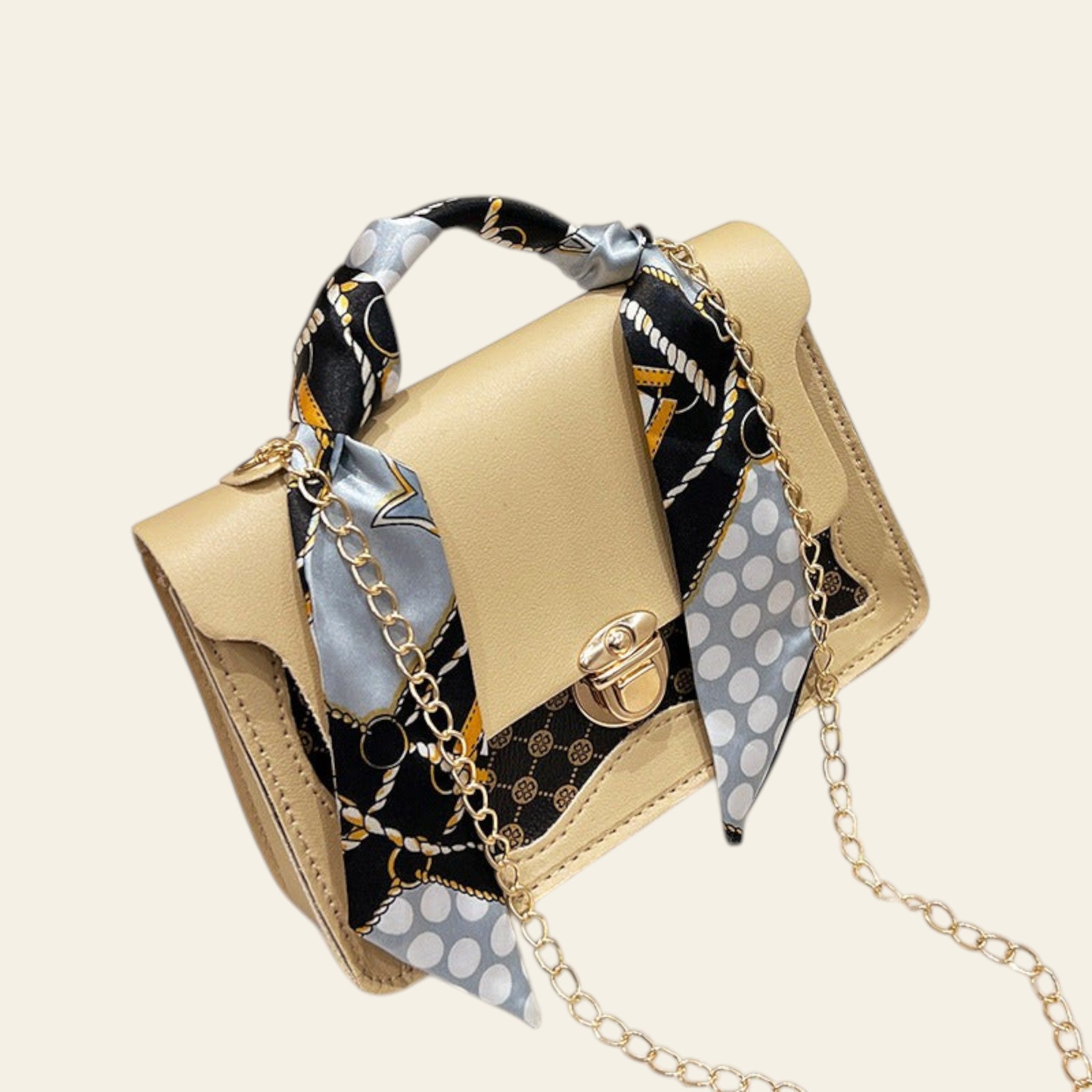 Beige handbag with a patterned scarf and gold chain strap on a white surface.