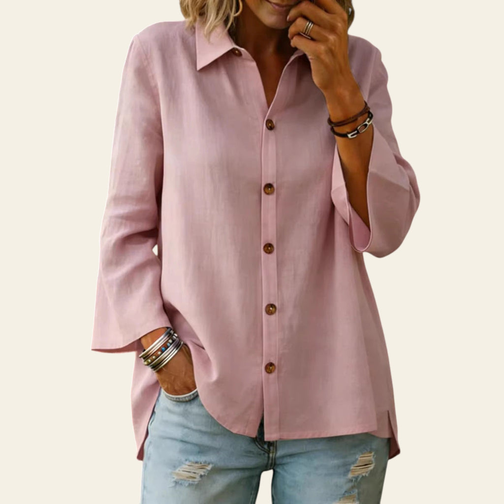 Person wearing a pink button-up shirt and light blue jeans with a blurred background