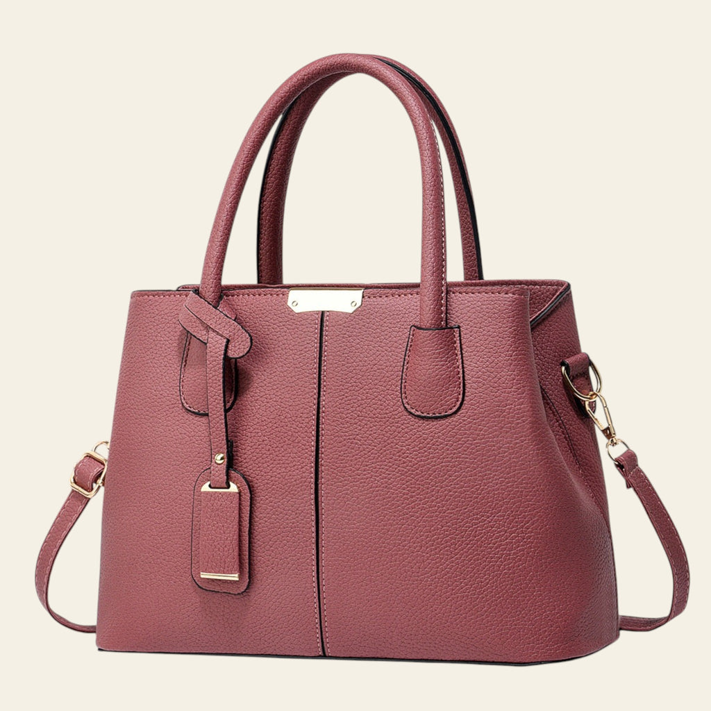 Pink handbag with gold accents on a white background