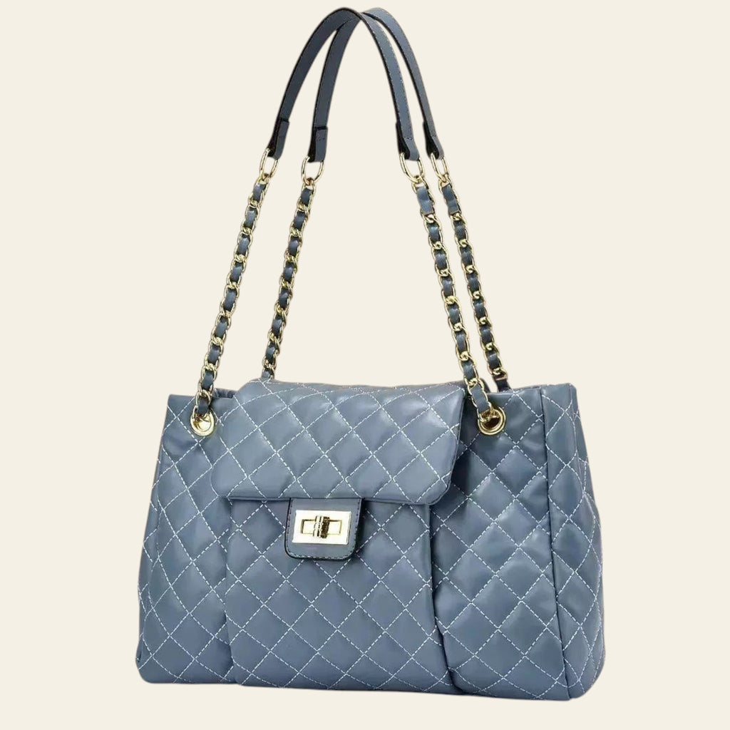 Blue quilted handbag with braided handles on a beige background