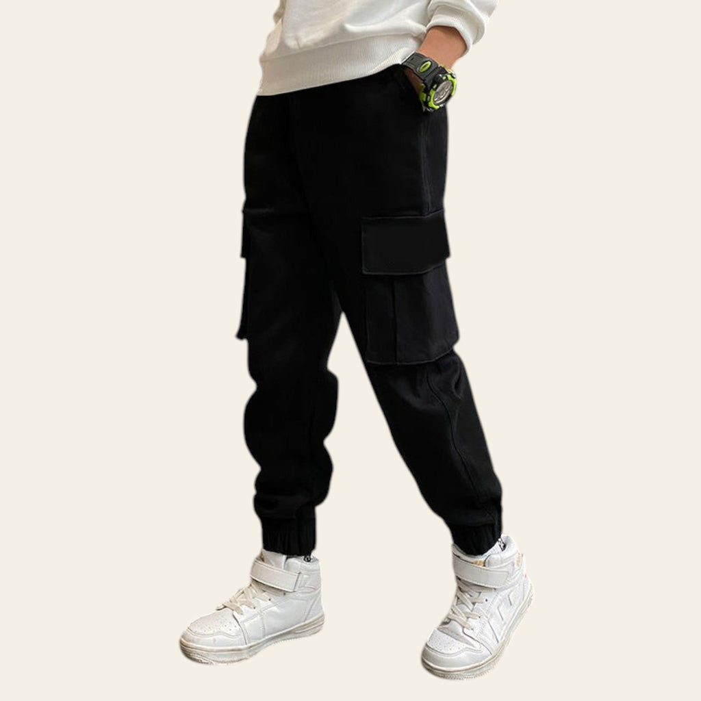 Person wearing black cargo pants and white sneakers in an indoor setting